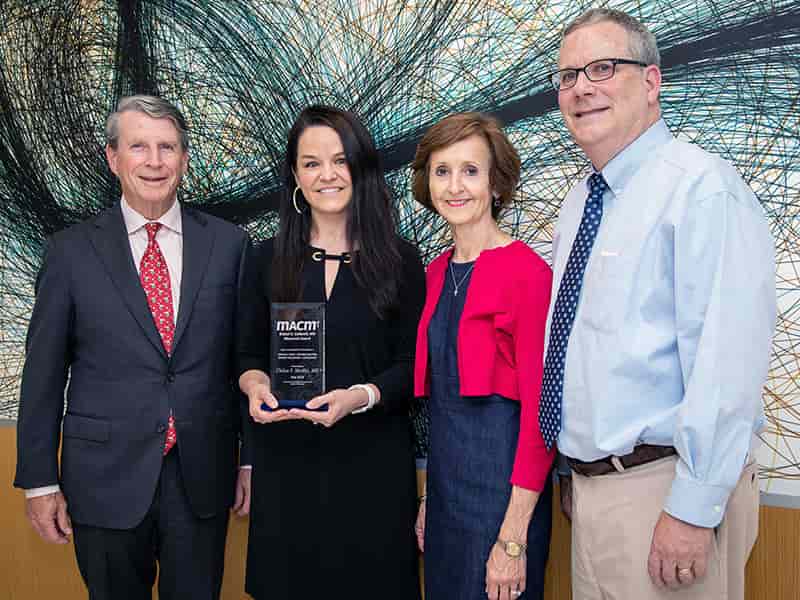 Dr. Chelsea S. Mockbee, second from left, receives the Caldwell Award from Dr. Eric A. McVey, left, chairman of the MACM Board of Directors and Dr. Gerry Ann Houston, MACM medical director, while Dr. Robert T. Brodell, UMMC professor and chair of dermatology, observes.